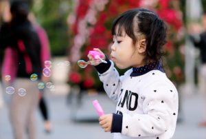 Have fun with Bubbles this Summmer! A toddler blowing bubbles in the park.