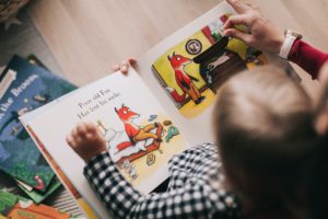 Read Interactive Books to Develop Language Skills Young Boy Reading Picture Book with Help From An Adult