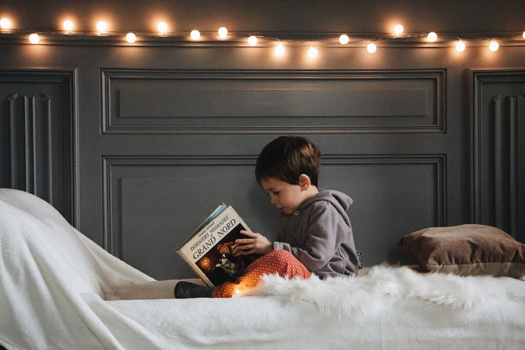 Child reading a book in bed