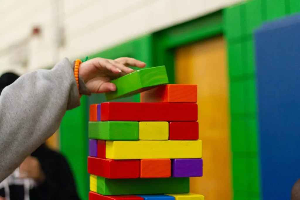 Close up of child's hand stacking colorful wooden blocks