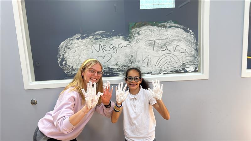 Therapist and child making handprints on a chalkboard