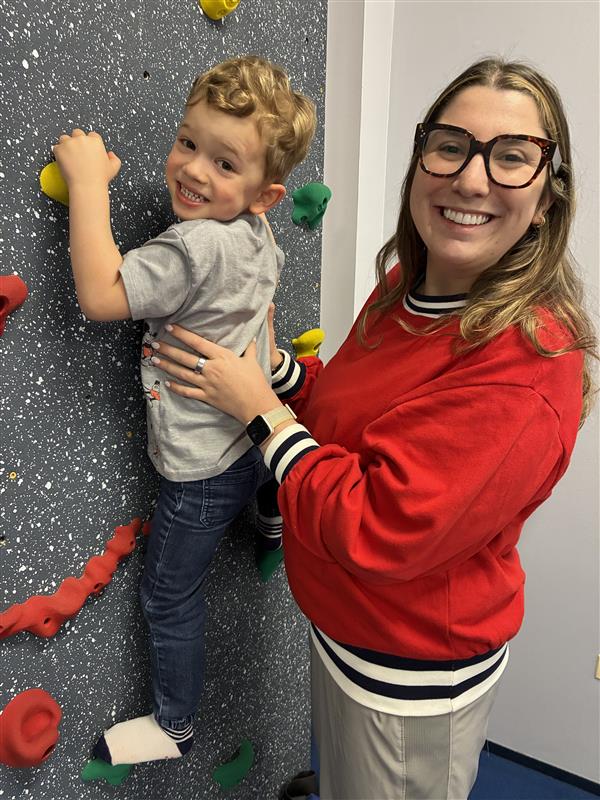 Child climbing a wall with a therapist