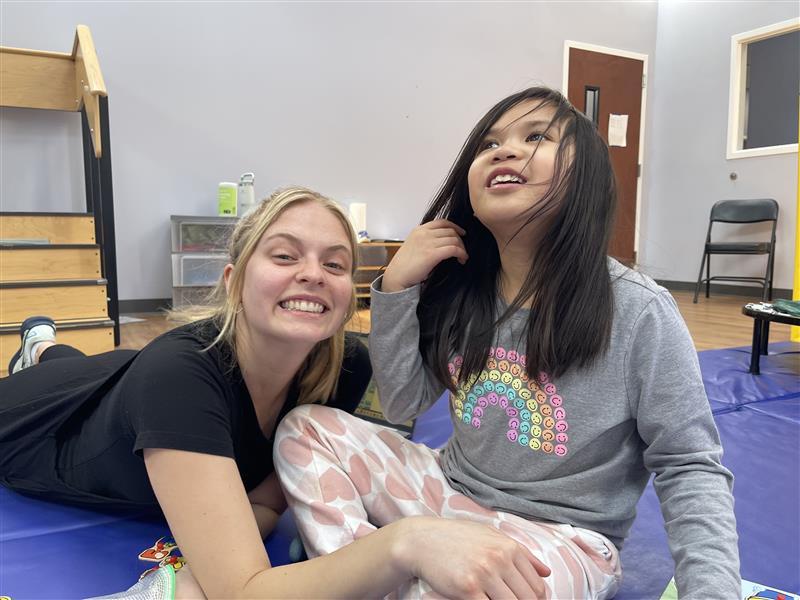 Therapist and child smiling on a mat