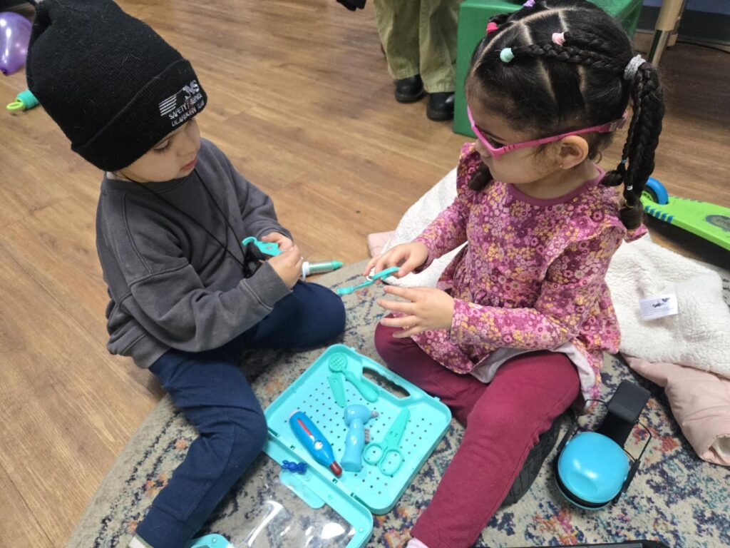 Two children playing with toys together on the floor